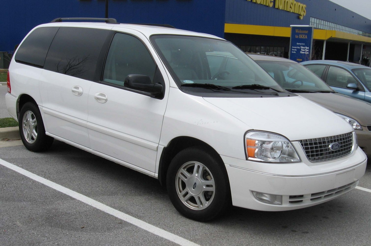 Front side view of white minivan with distinct headlights and grille