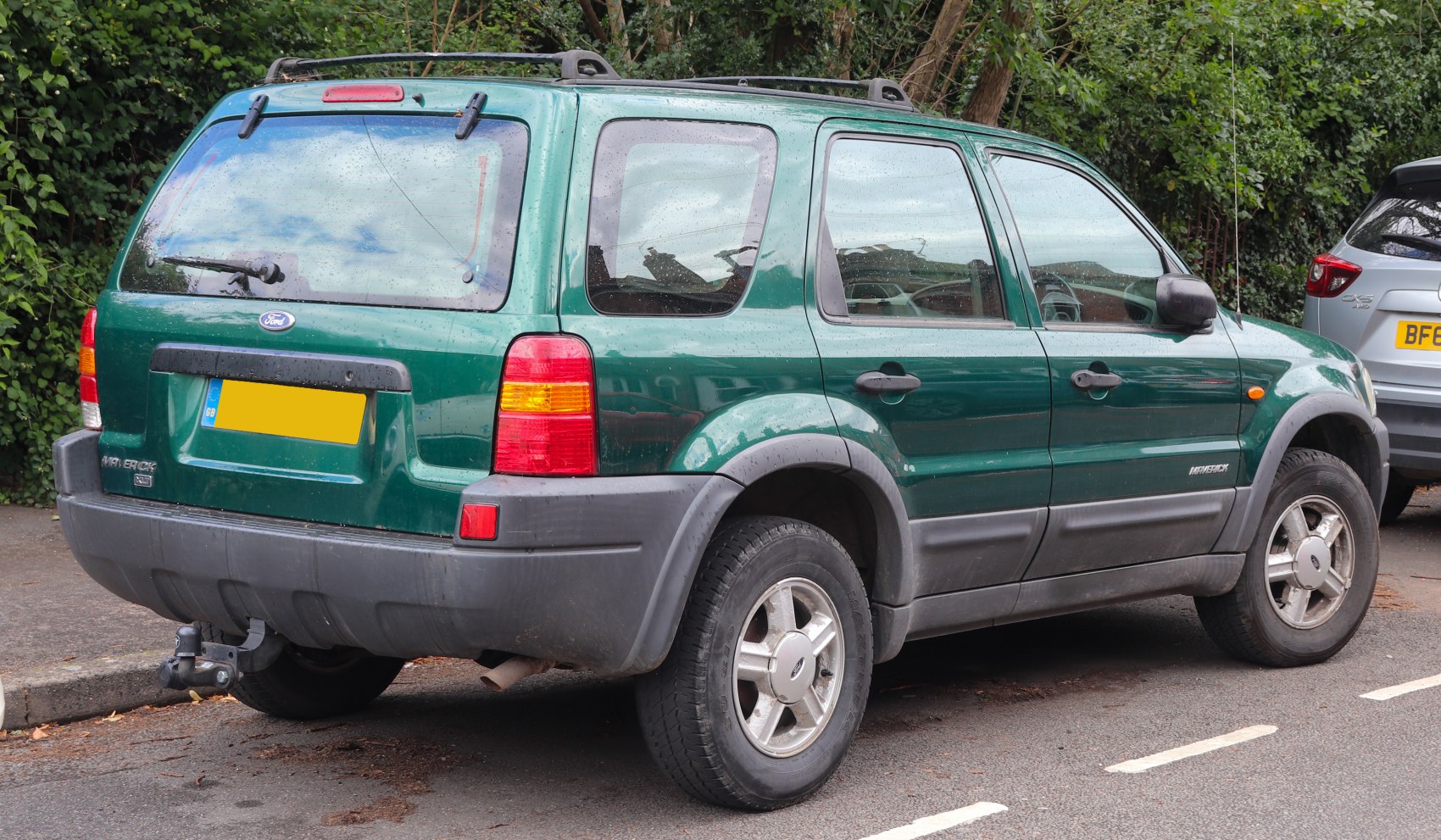 Rear side view of green SUV with tow hitch and taillights