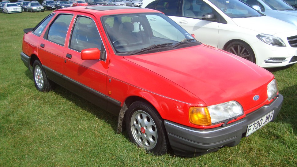 Red hatchback with rectangular headlights and alloy wheels