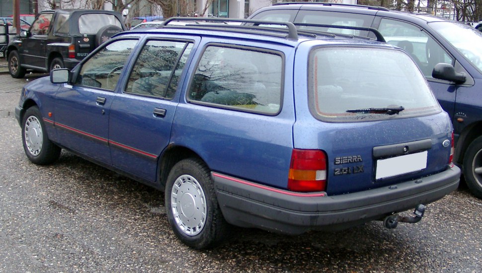 Rear-side view of a classic blue station wagon with roof rails and distinctive tail lights