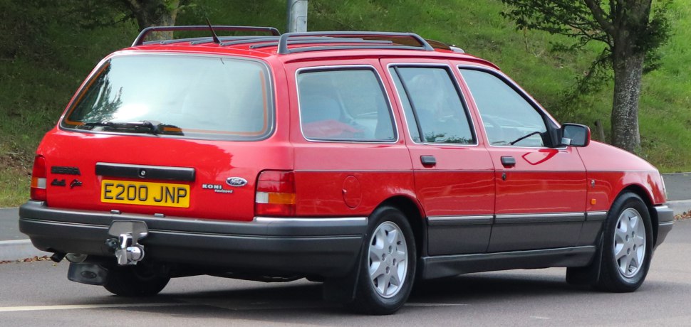 Rear and side view of red station wagon with roof rails and tow hitch
