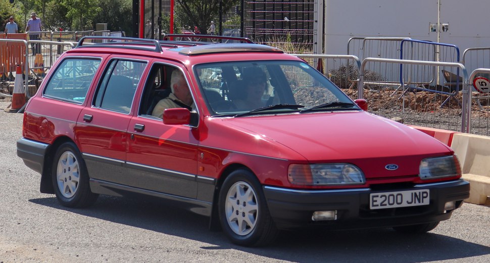 Red station wagon with roof rails and alloy wheels shown from front side.