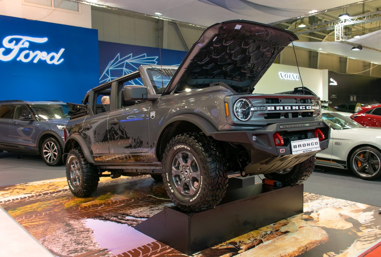 Four-door SUV with off-road tires and open hood on display