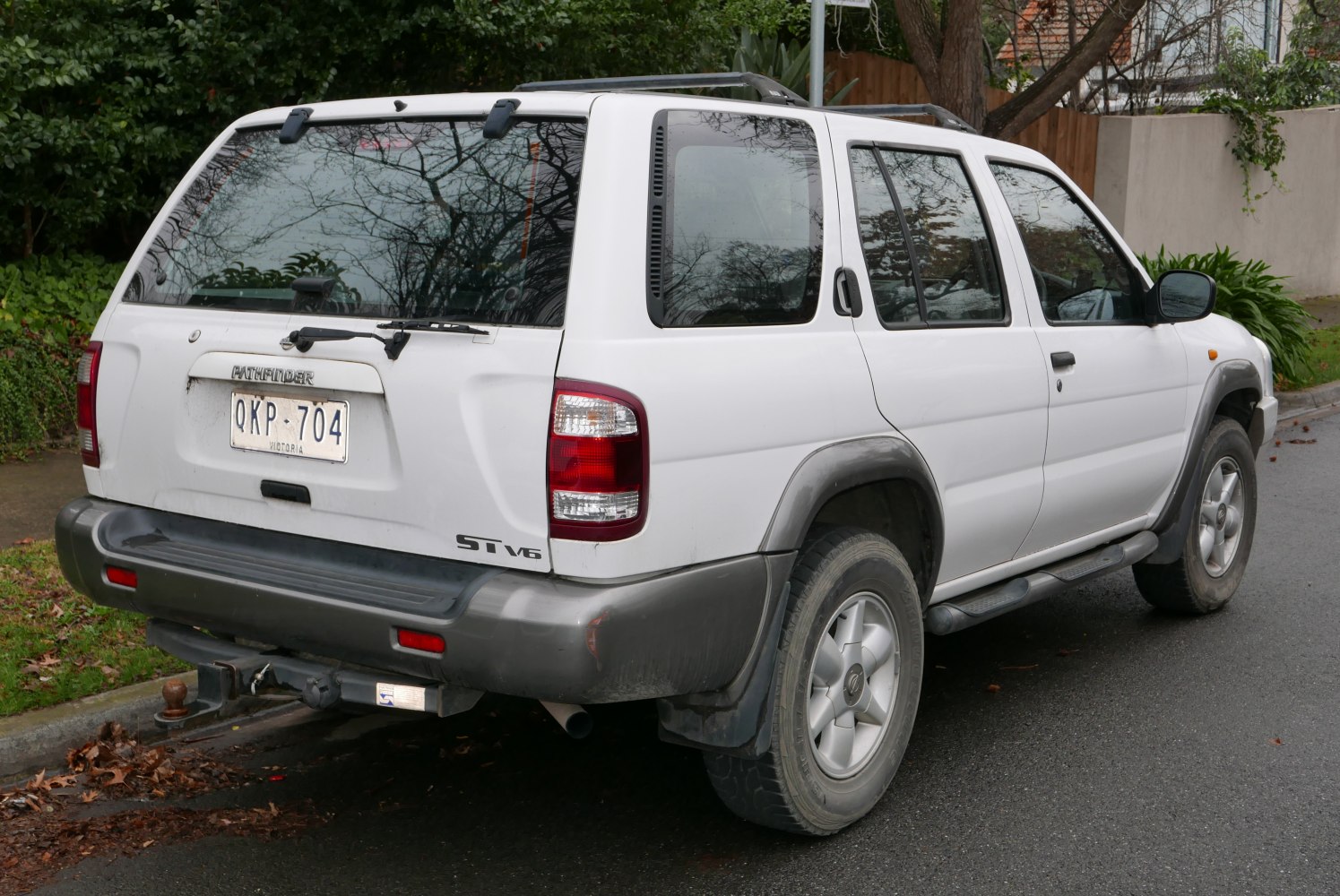 Rear side view of white SUV with large taillights and roof rails