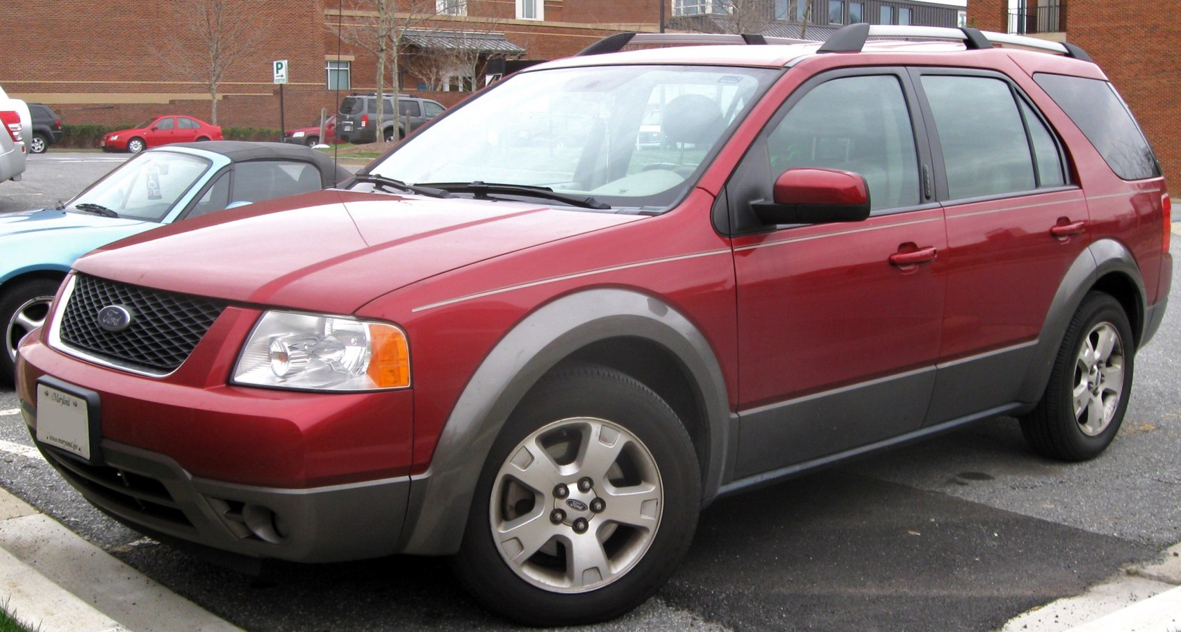 Front side view of red SUV with alloy wheels and protective body cladding