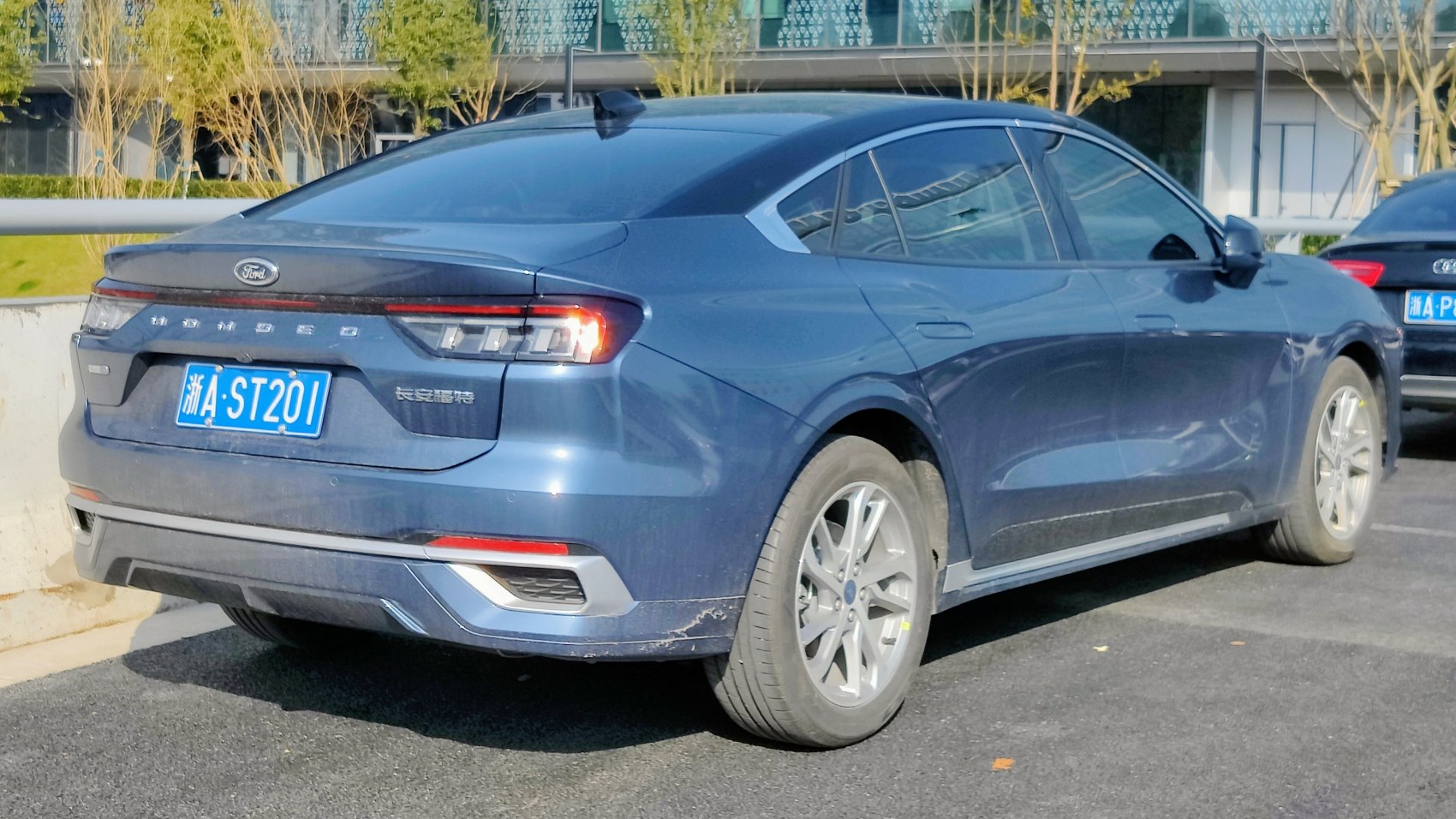 Rear and side of modern mid-size sedan with sleek tail lights and alloy wheels