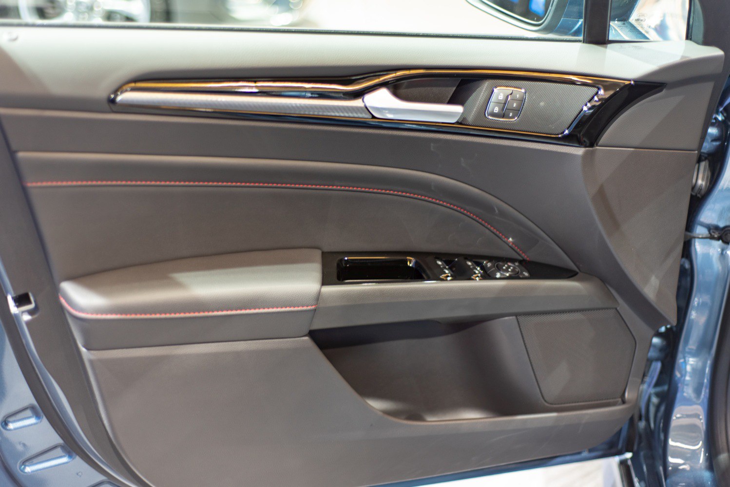 Interior door panel with red stitching, lock buttons, and window controls