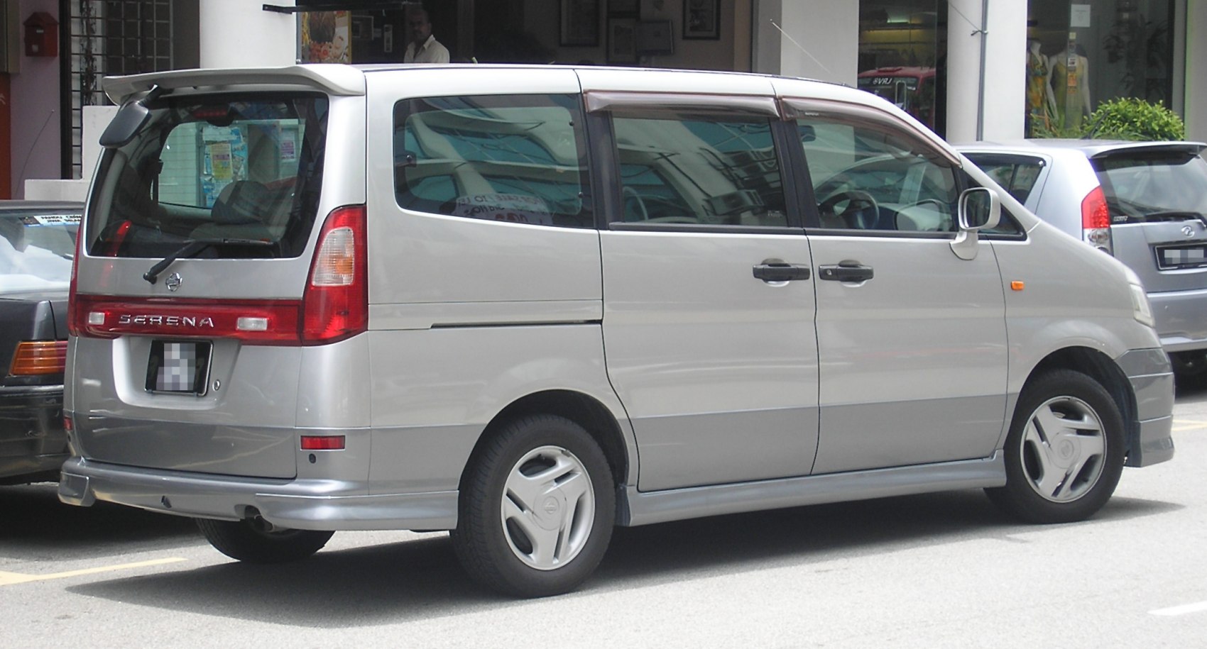 Silver minivan rear and side view with sliding doors and rear spoiler.
