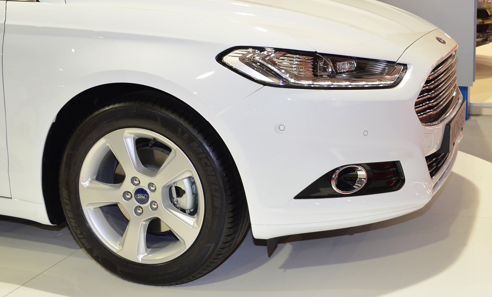 Front side showing alloy wheel, headlight, grille, and fog light.