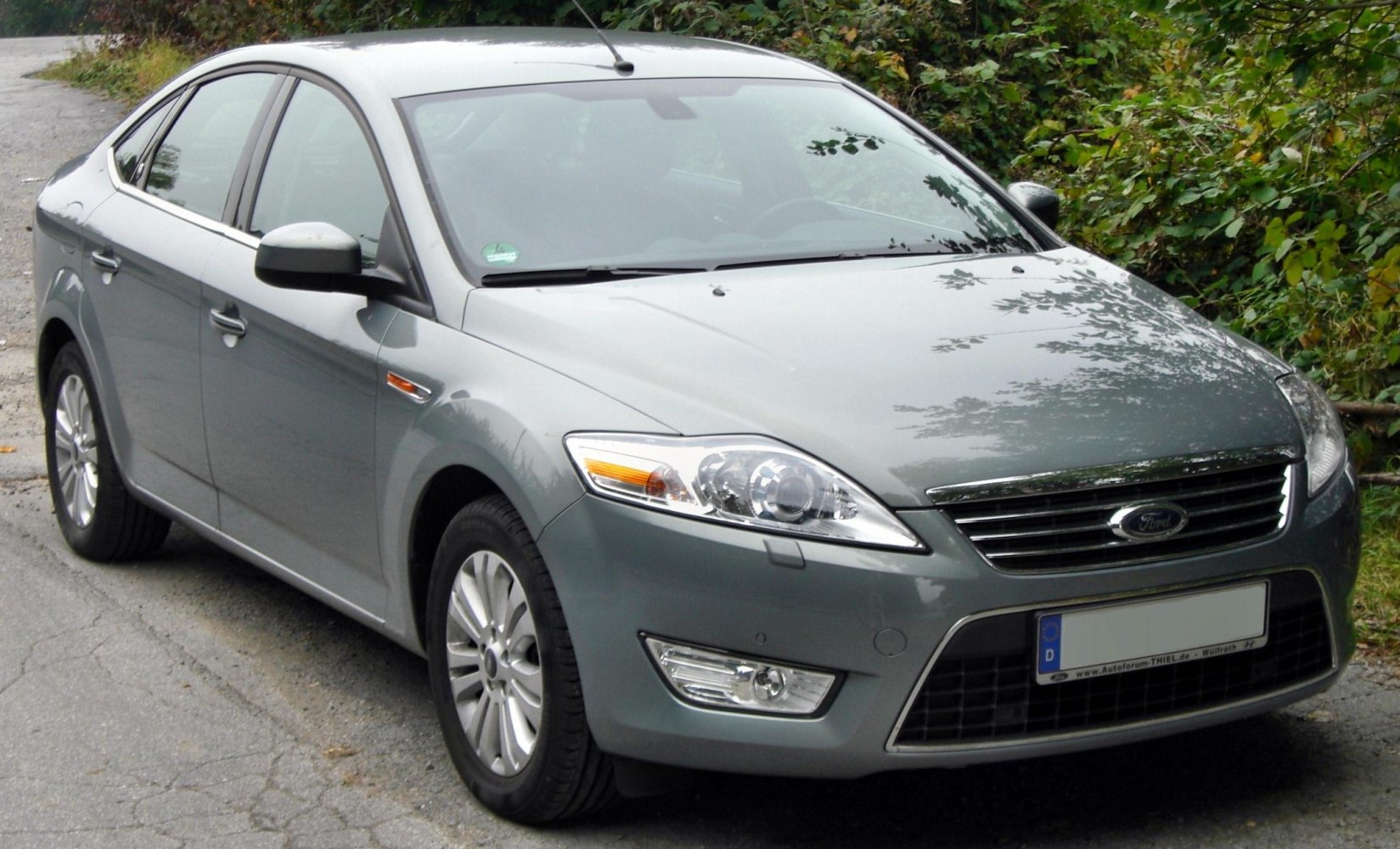 Front and side profile of a modern mid-size hatchback with clear headlights and alloy wheels.