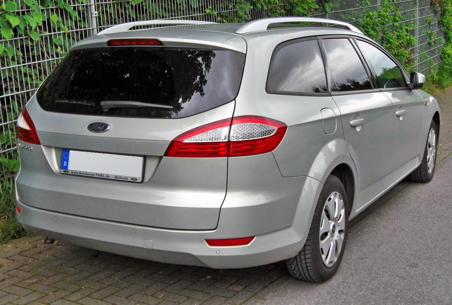 Rear and side view of silver station wagon with distinct tail lights and roof rails