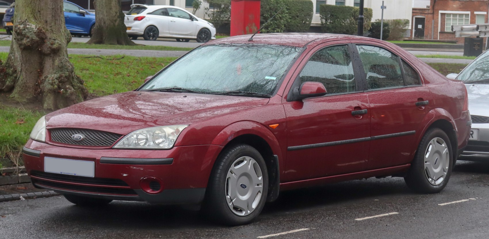 Red four-door hatchback with detailed headlights and silver wheel covers.