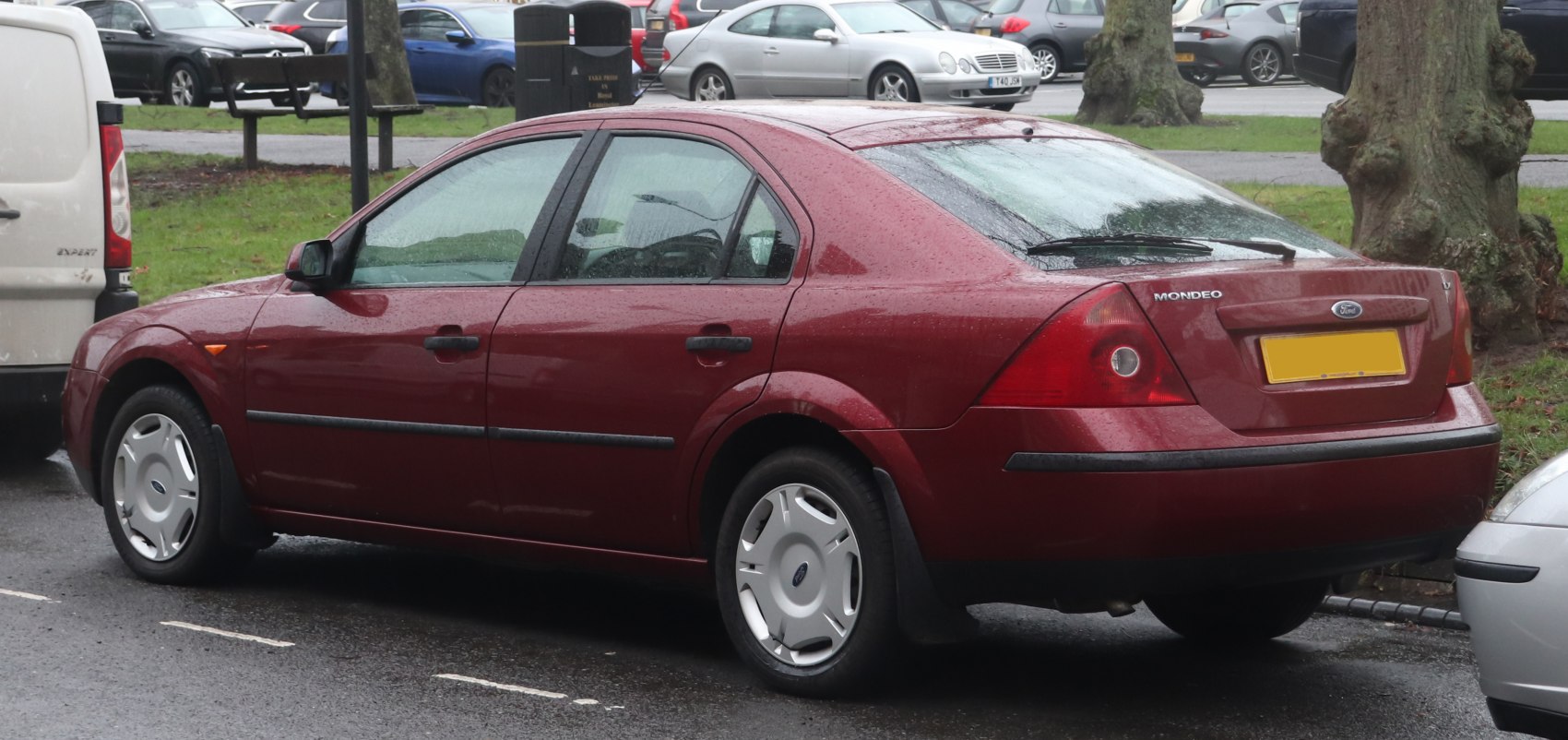 Rear side view of red hatchback with focus on rear lights and wheels