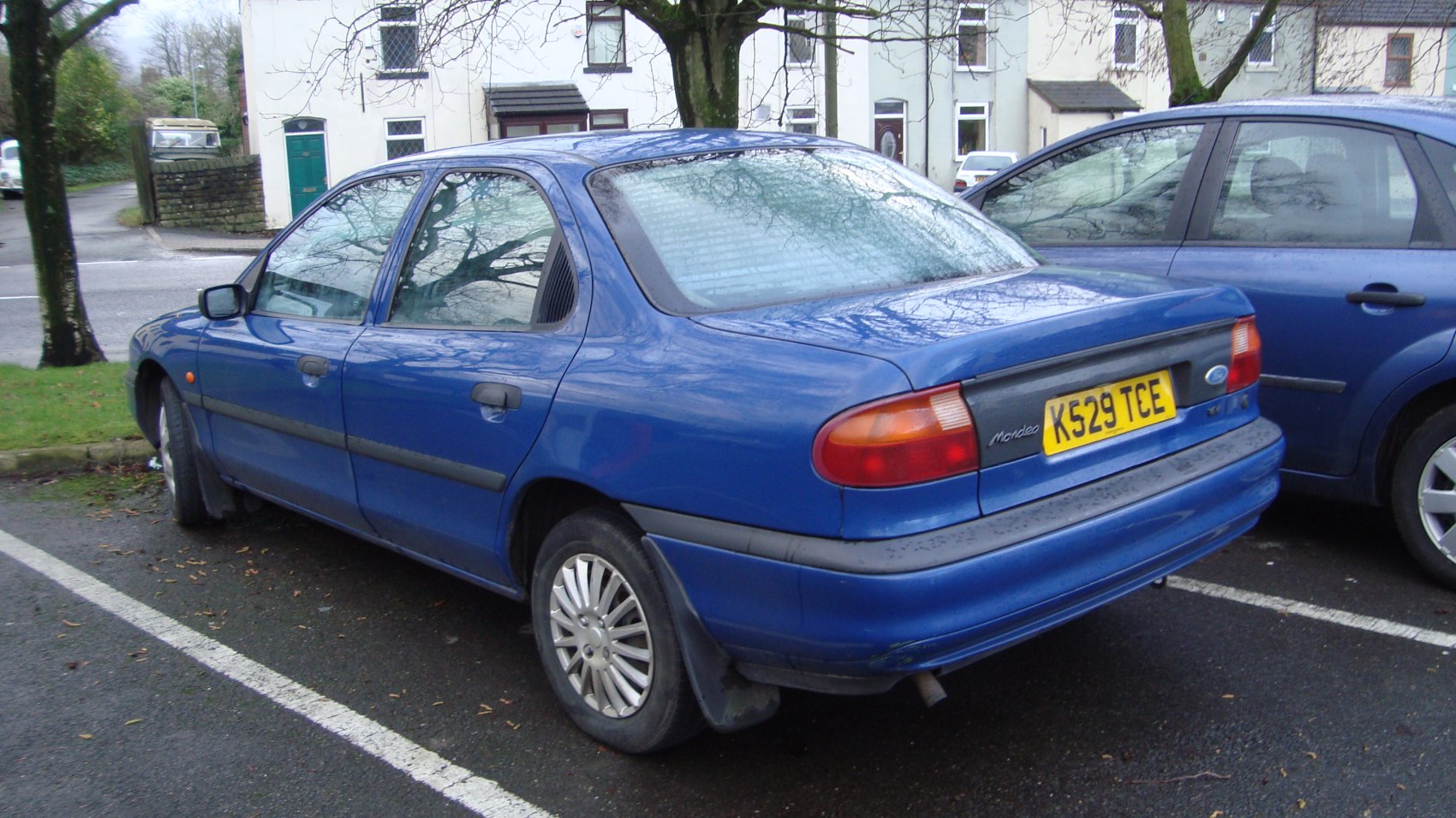 Rear side view of blue 1993 four-door sedan with visible taillights.