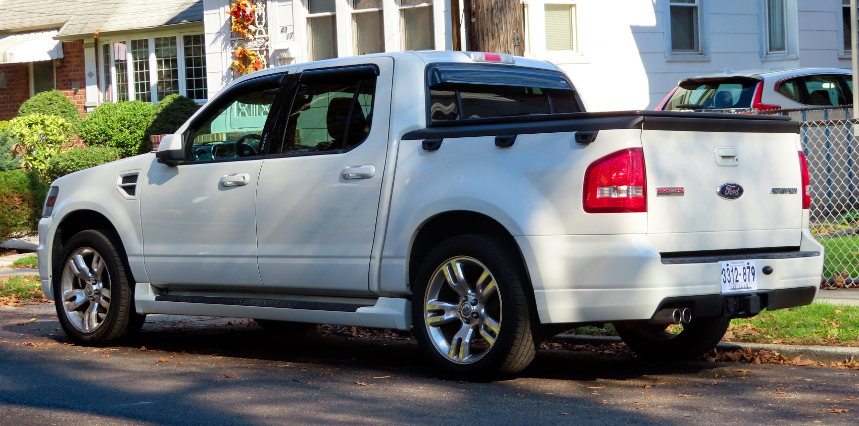 White four-door pickup truck rear and side profile with dual exhaust and alloy wheels