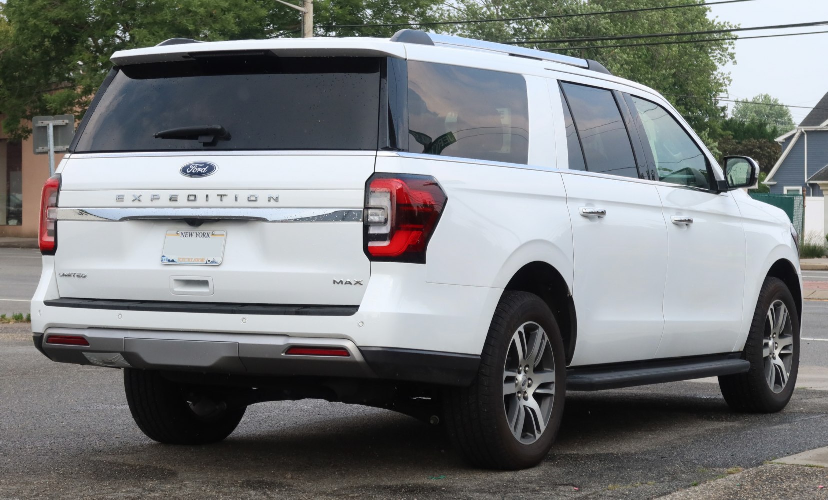 Rear perspective of a large white SUV with distinct taillights and roof rails
