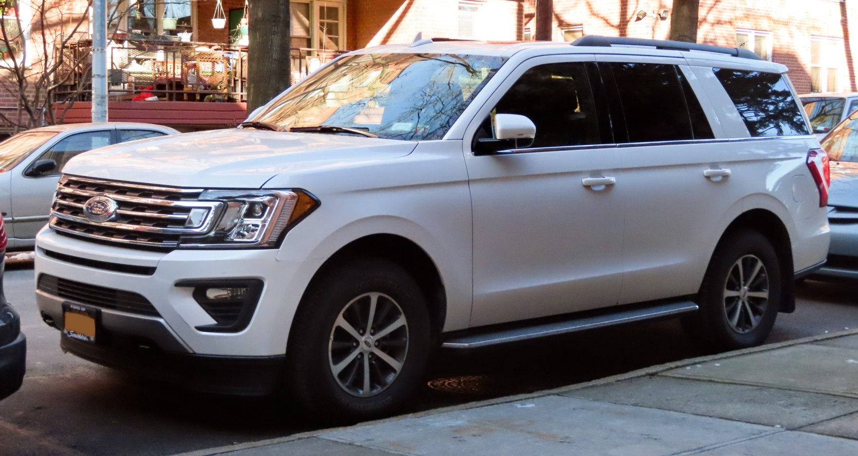White SUV with chrome grille, alloy wheels, tinted windows parked on street