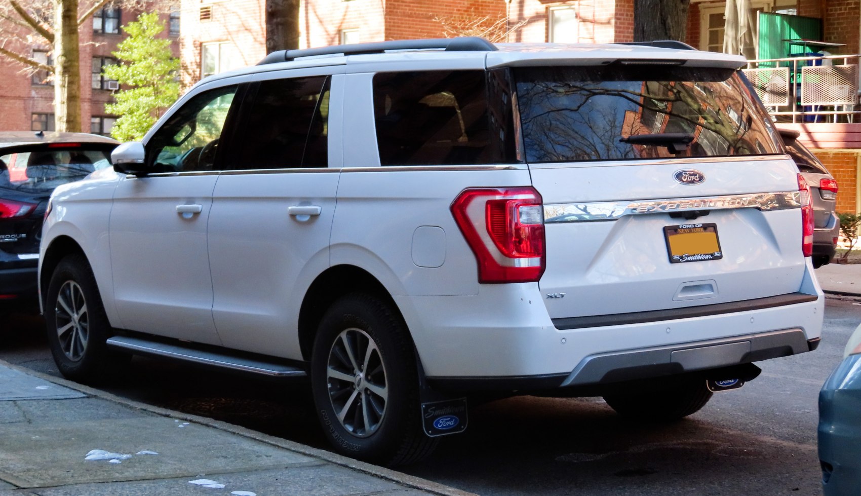 White full-size SUV rear with roof rails and alloy wheels