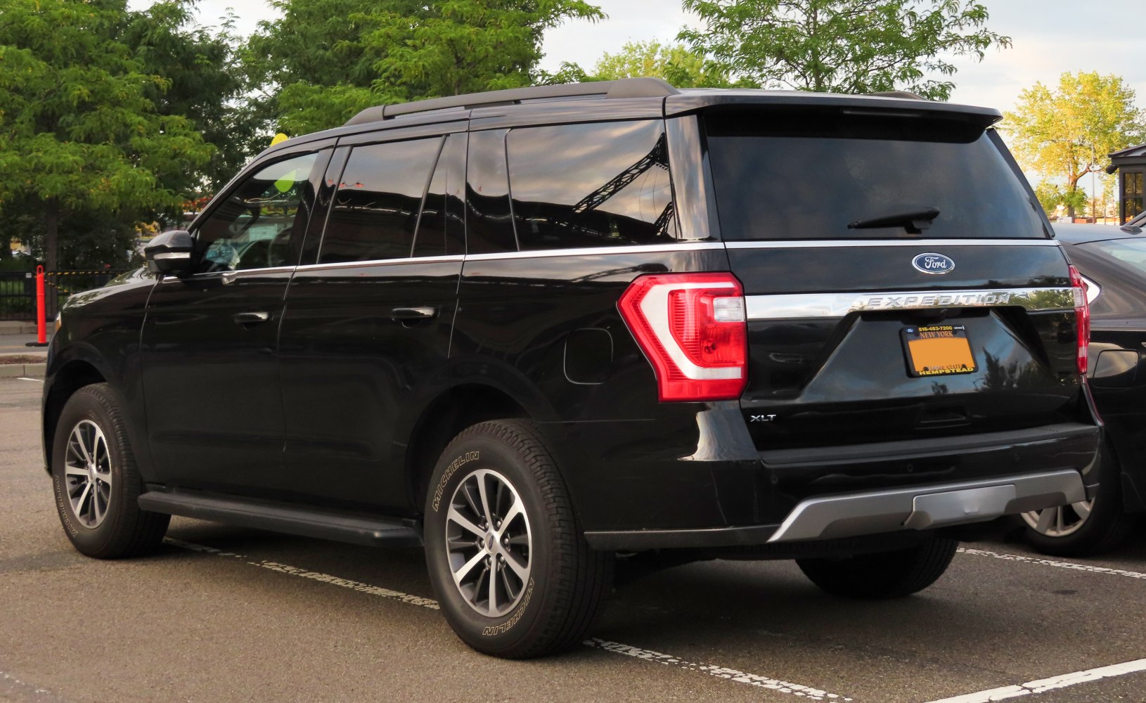Rear side view of black full-sized SUV with dark tinted windows and modern taillights
