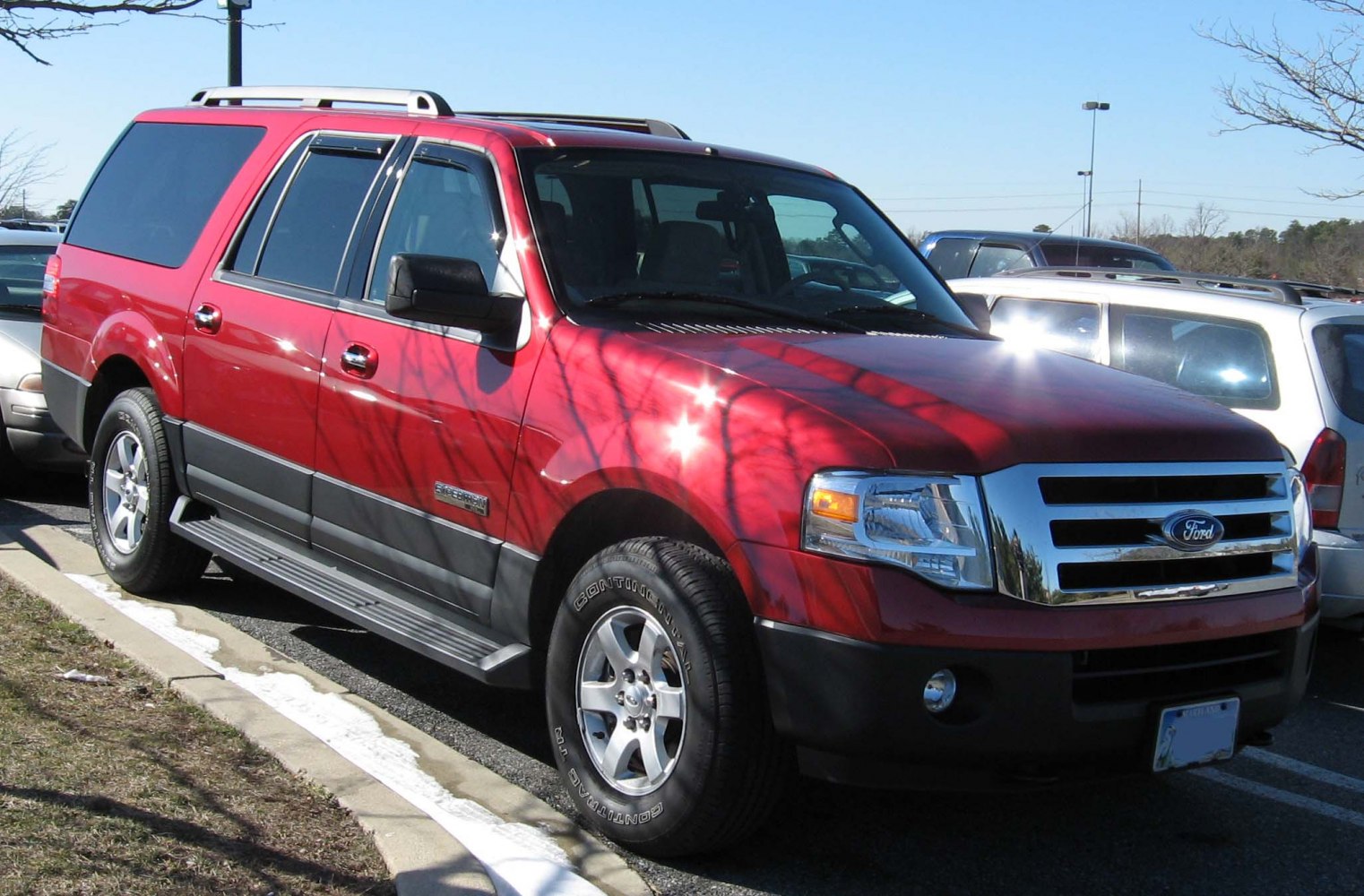 Red large SUV with chrome grille, running boards and roof rails