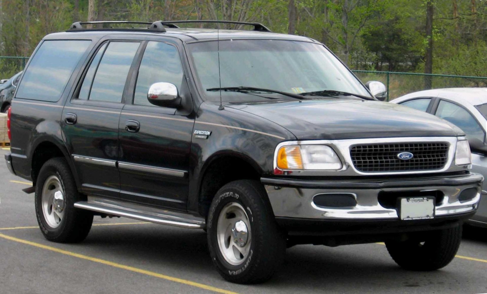 Full-size SUV with chrome bumper, roof rack, and side steps
