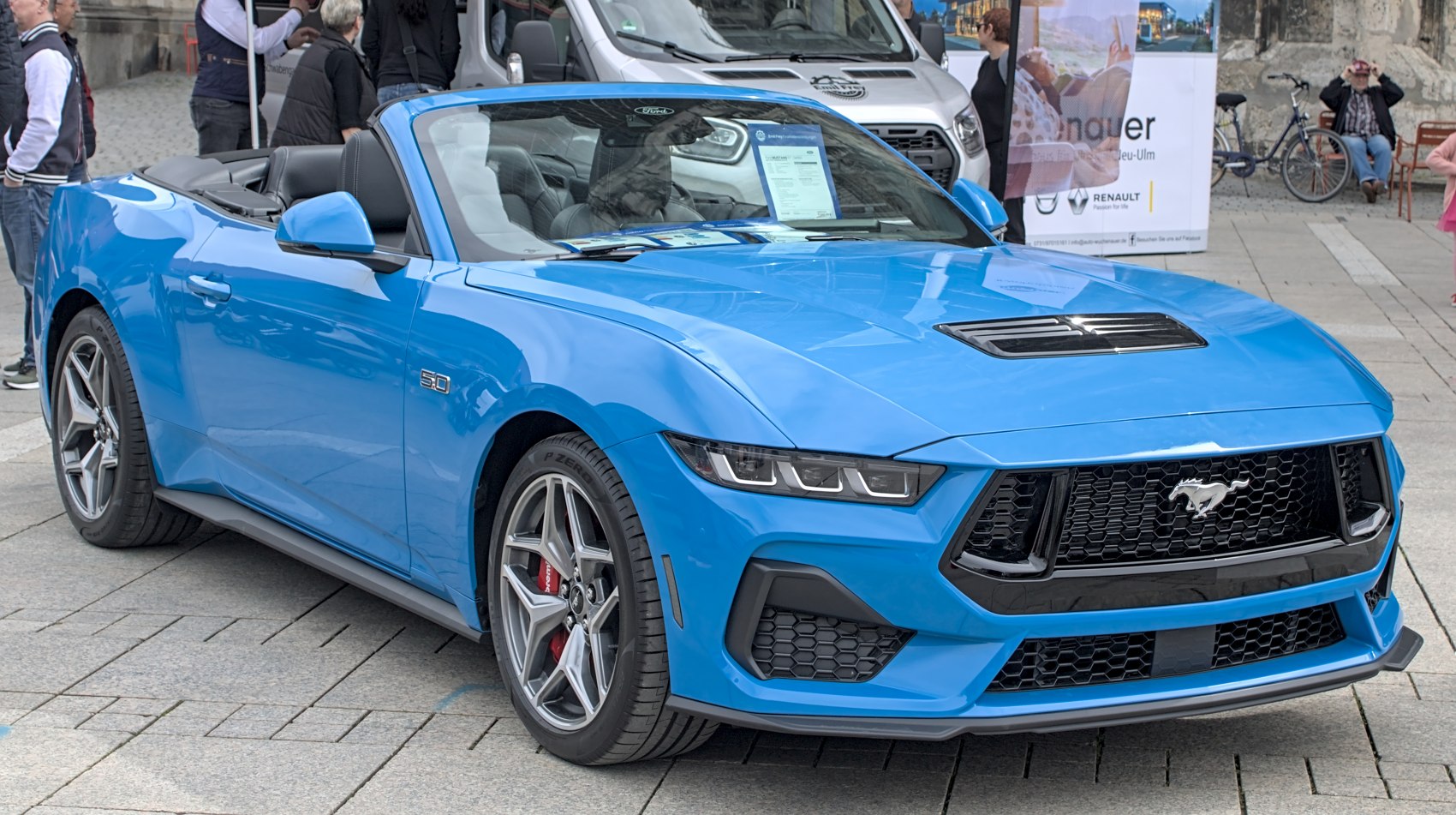 Blue convertible with open roof, LED headlights, black honeycomb grille.