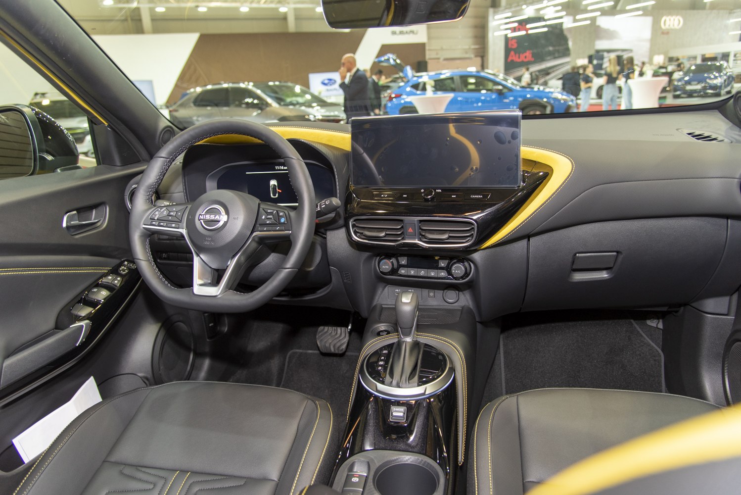 Modern car interior with touchscreen, steering wheel controls, and yellow accent trim