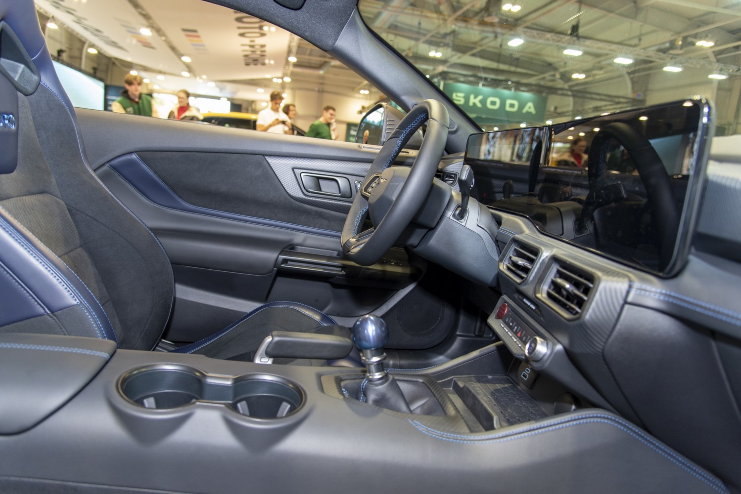Digital dashboard display and manual gear shifter with blue stitching