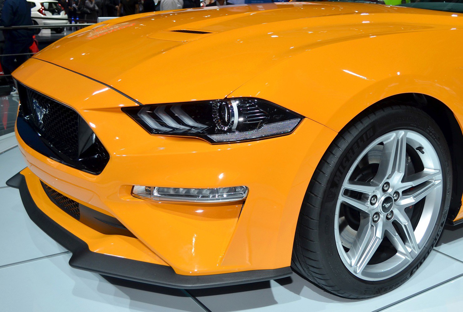 Close-up of front grille, headlights, and alloy wheel of a sports car
