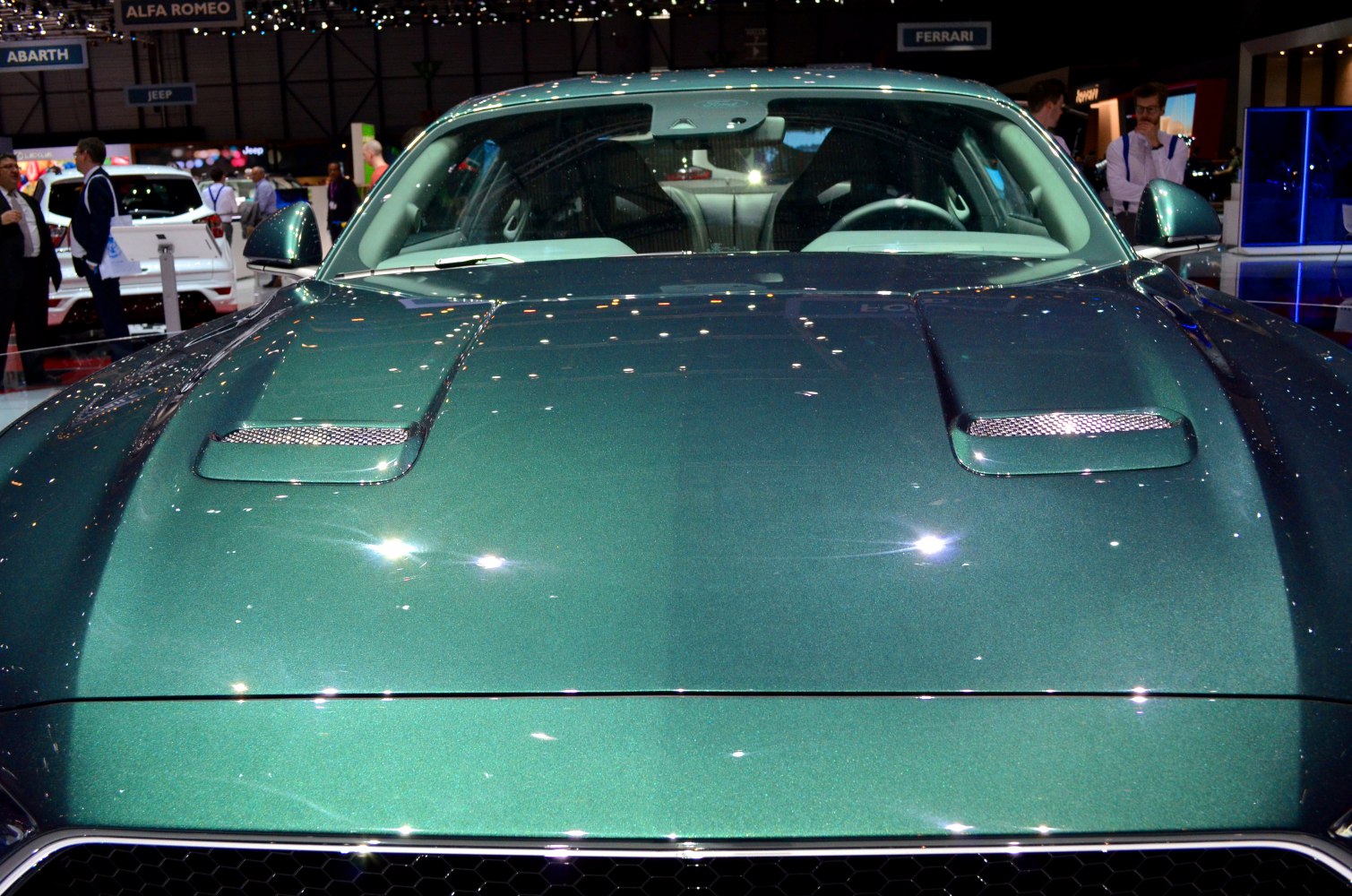 Sculpted hood with dual vents of a metallic green sports car.