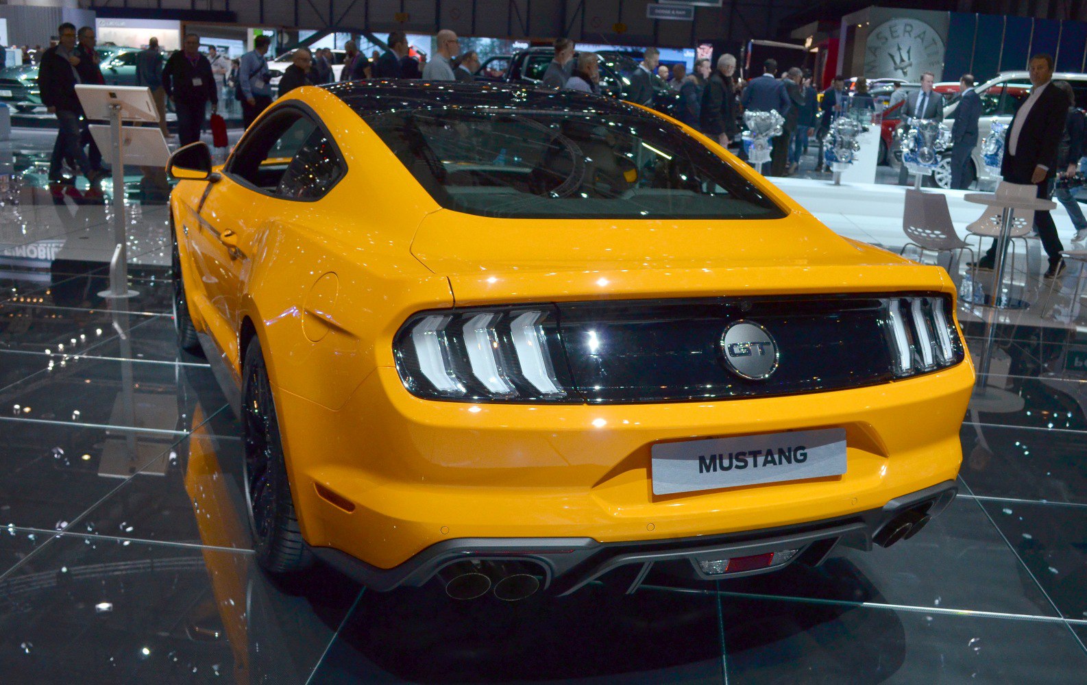 Rear view of a yellow muscle coupe with triple-bar taillights and quad exhaust.