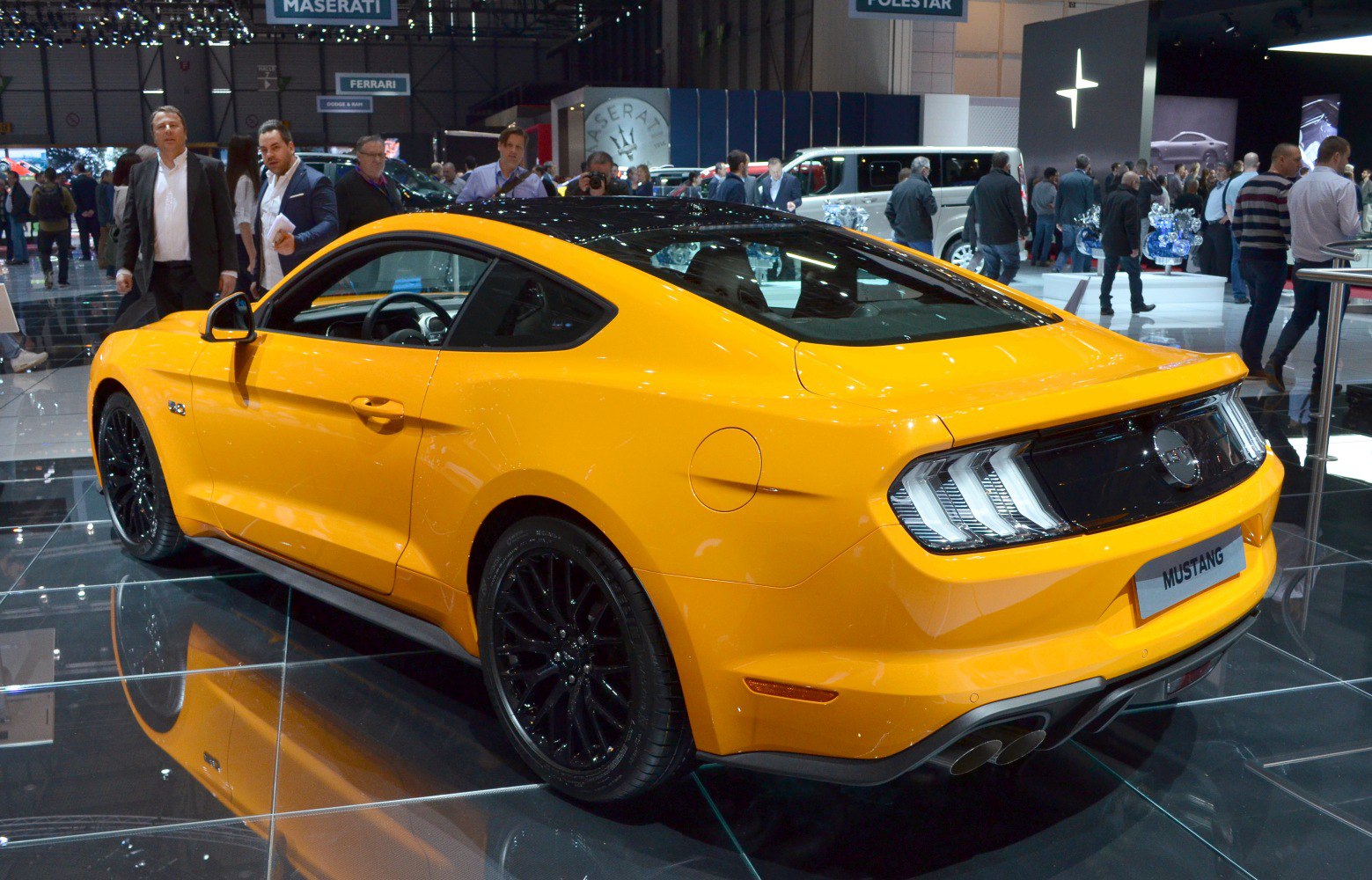 Rear three-quarter view of yellow muscle coupe with black wheels and signature taillights