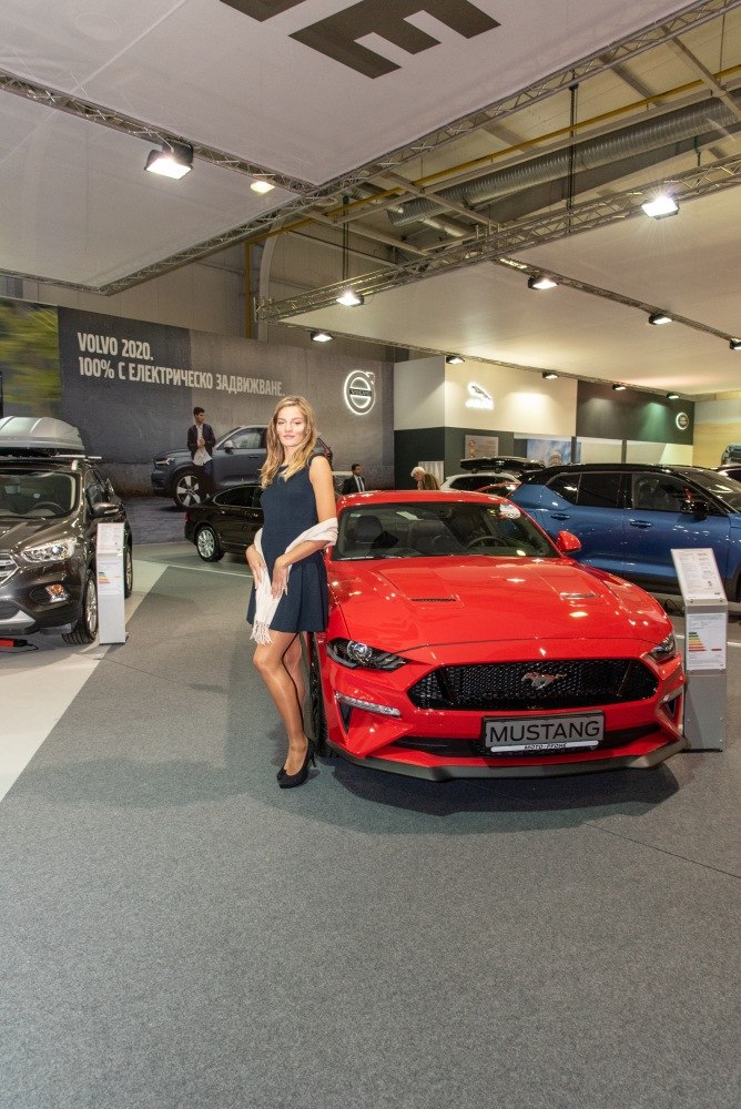 Red Mustang VI facelift front with woman at auto show