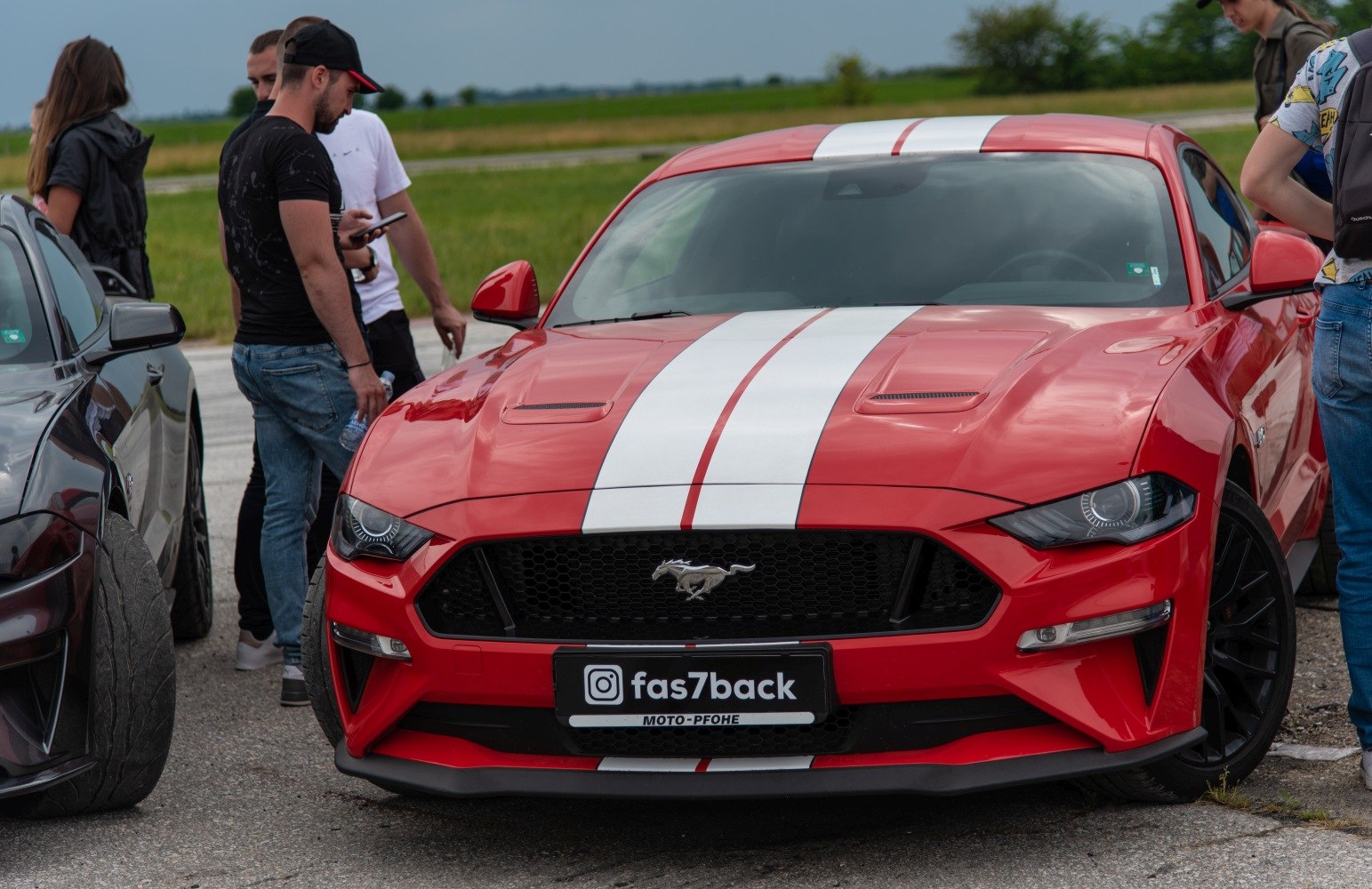 Front view of red sports car with white racing stripes