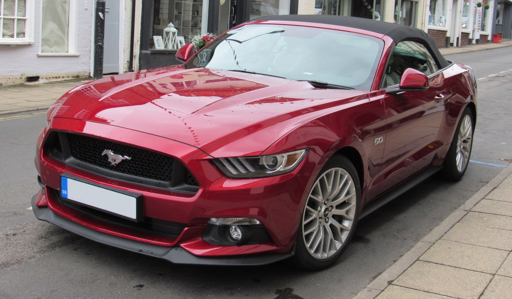 Convertible Ford Mustang with soft top and LED headlights.