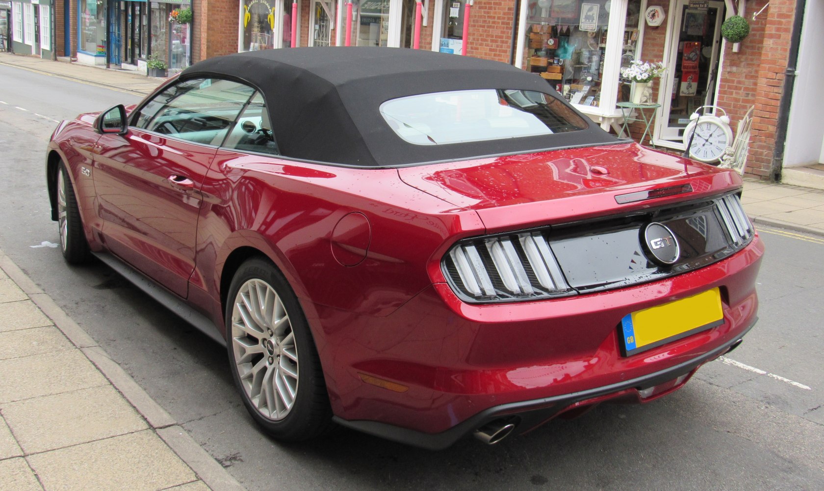 Rear view of red convertible with black fabric soft top and distinctive taillights