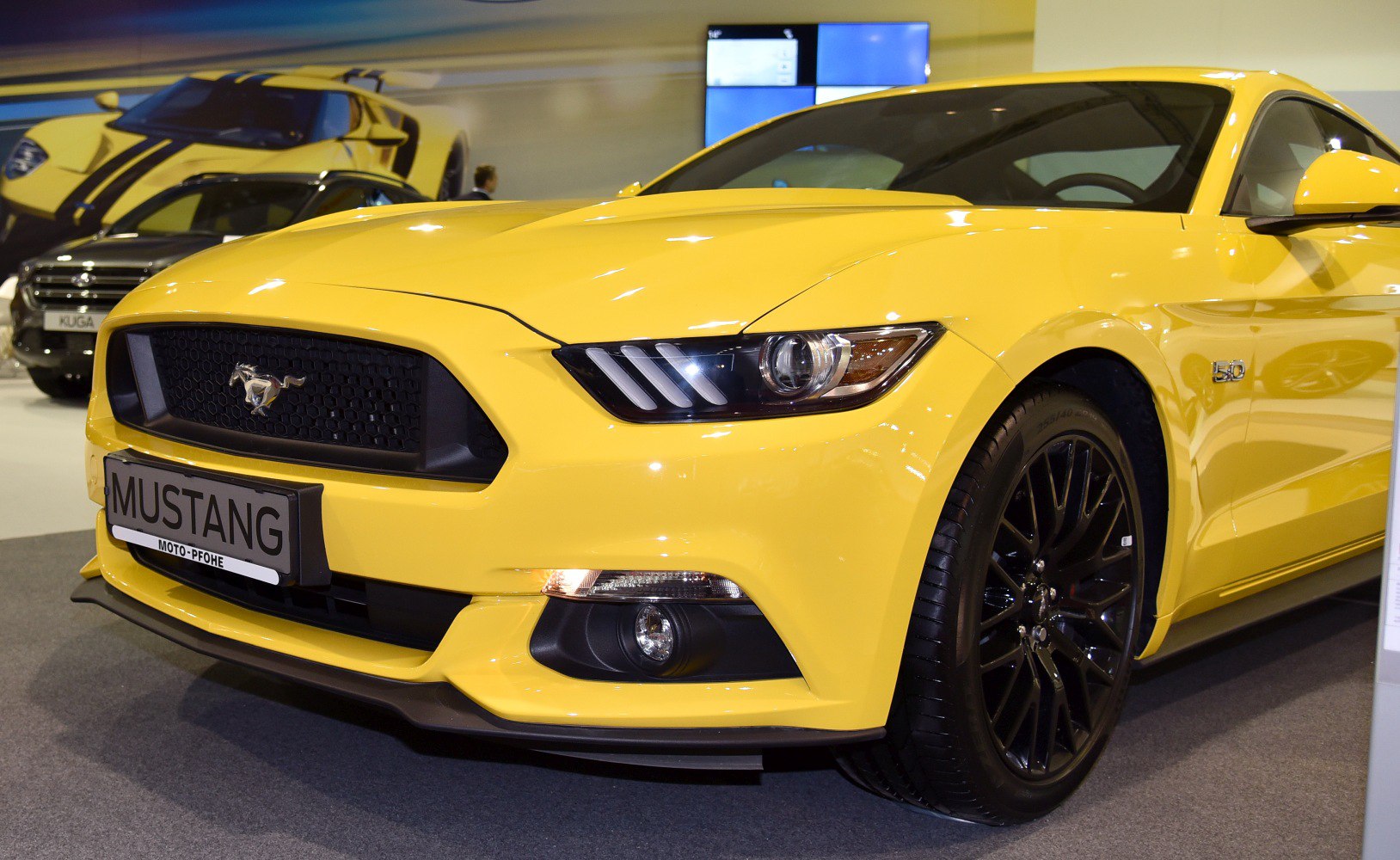 Close-up of yellow Mustang front with black grille and headlights