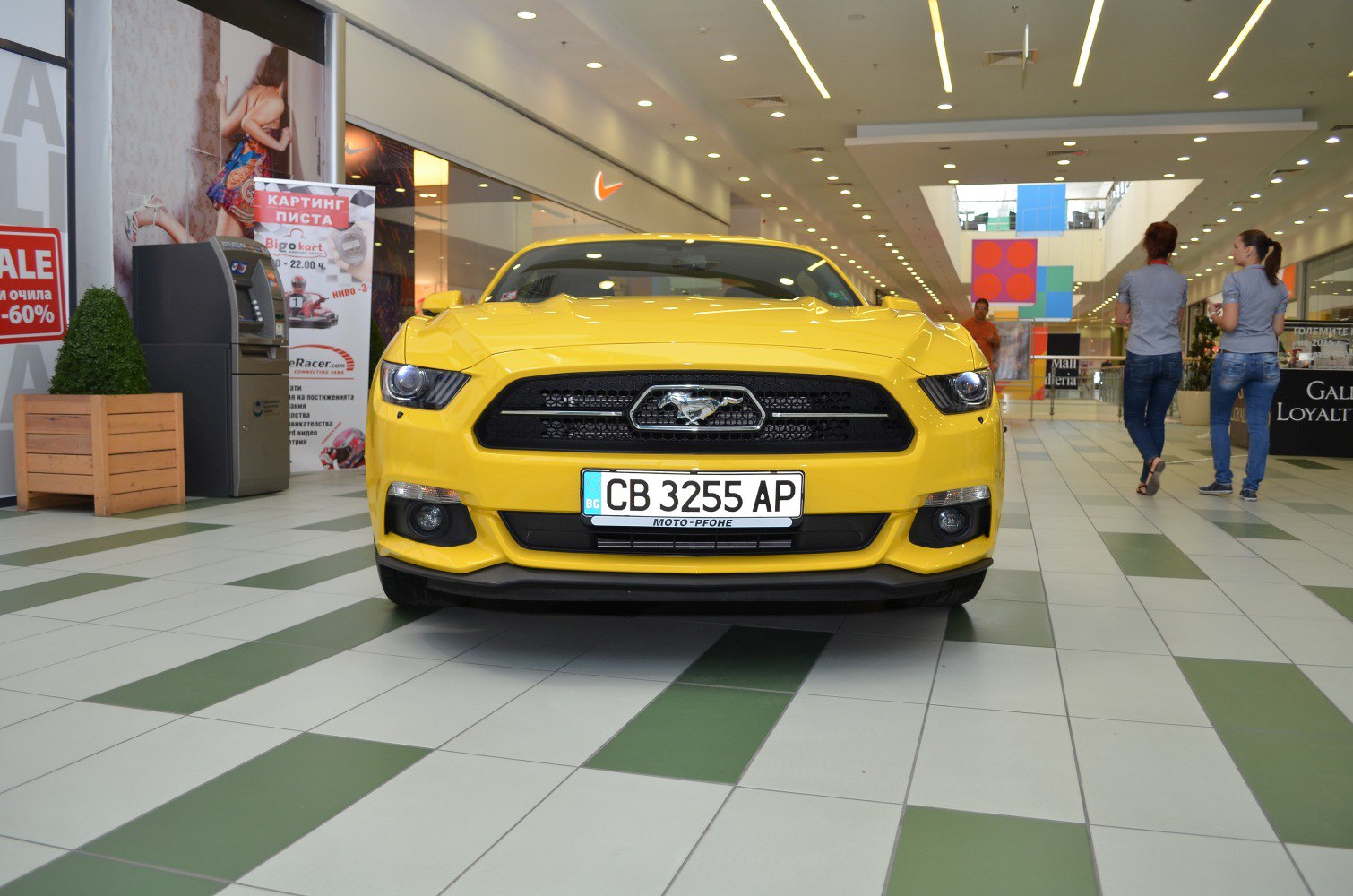 Yellow muscle car front with grille and headlights.