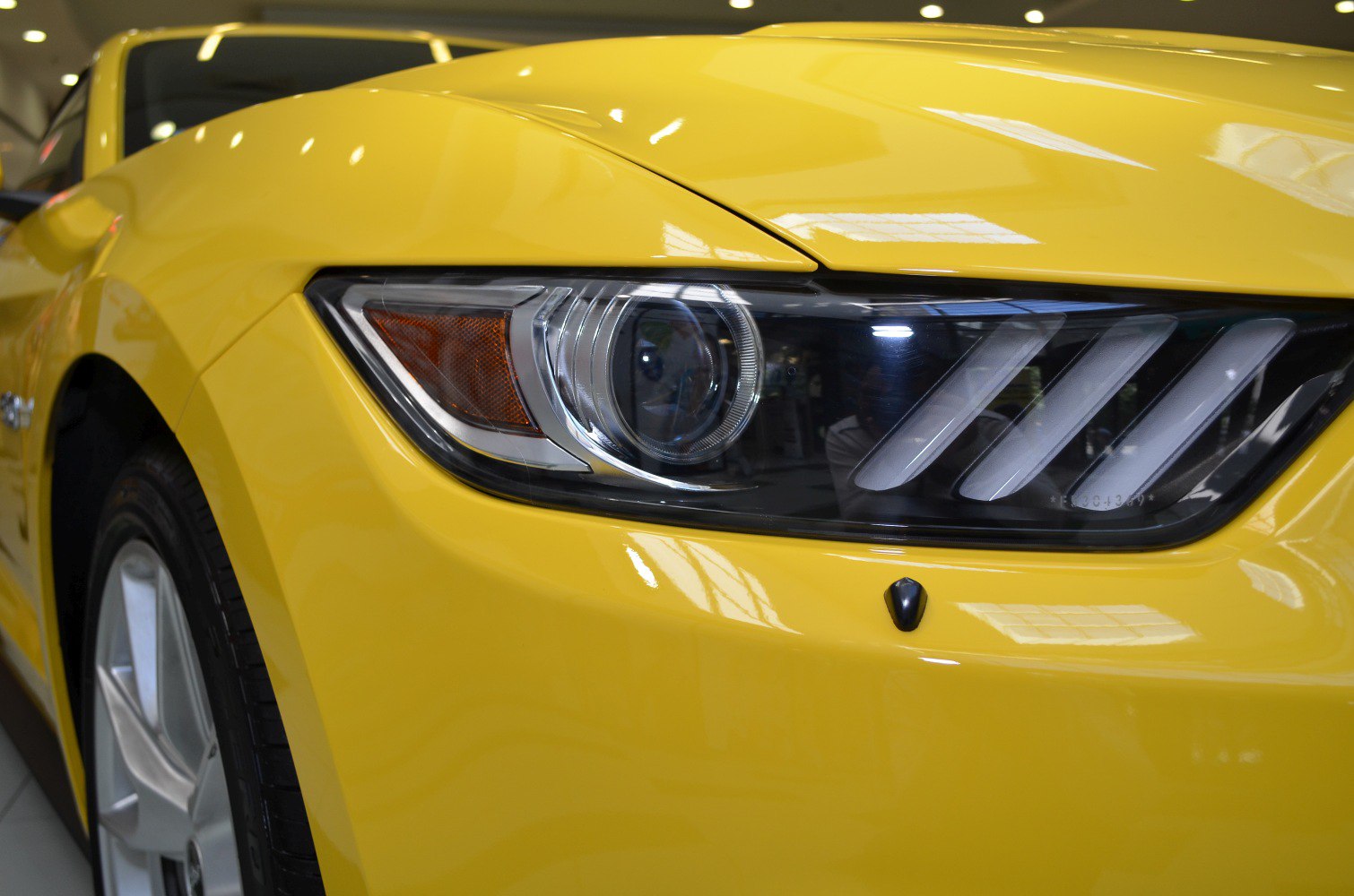Close-up of a sleek front headlight and yellow fender.