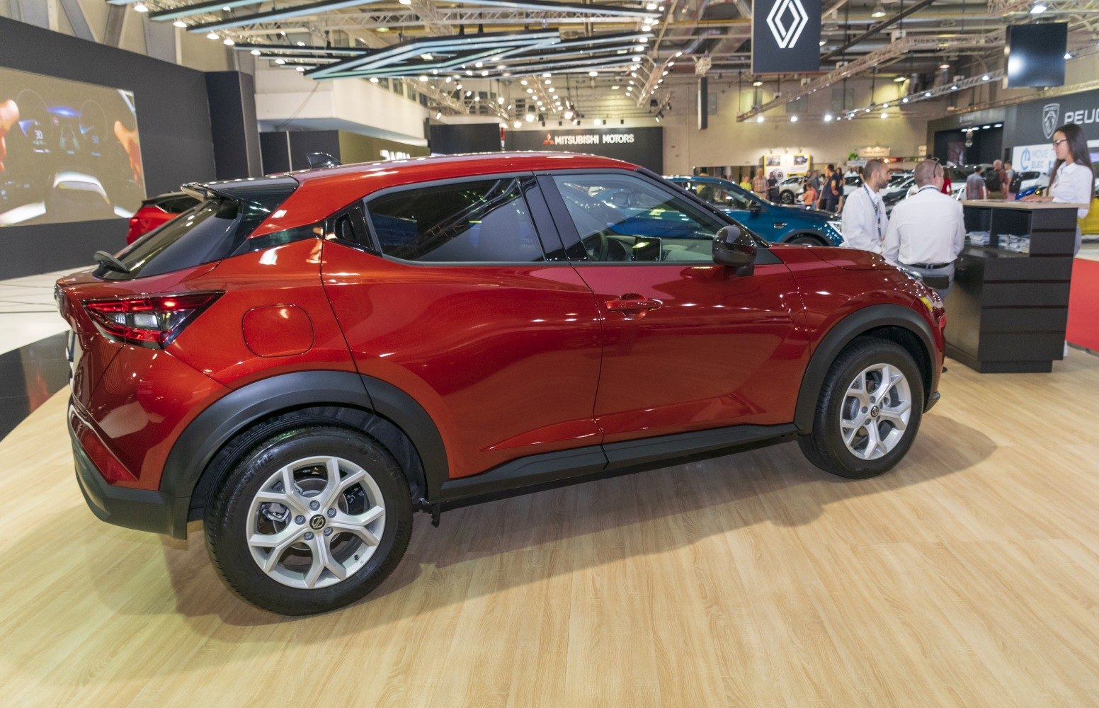 Side profile of red compact crossover SUV with alloy wheels and tinted windows.