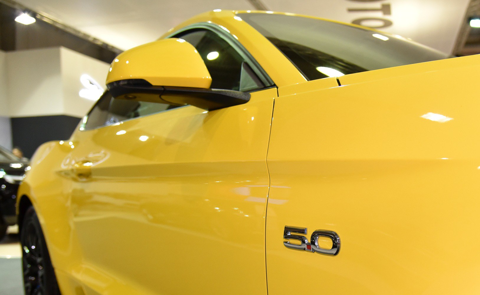 Side view with 5.0 badge and side mirror on yellow muscle car