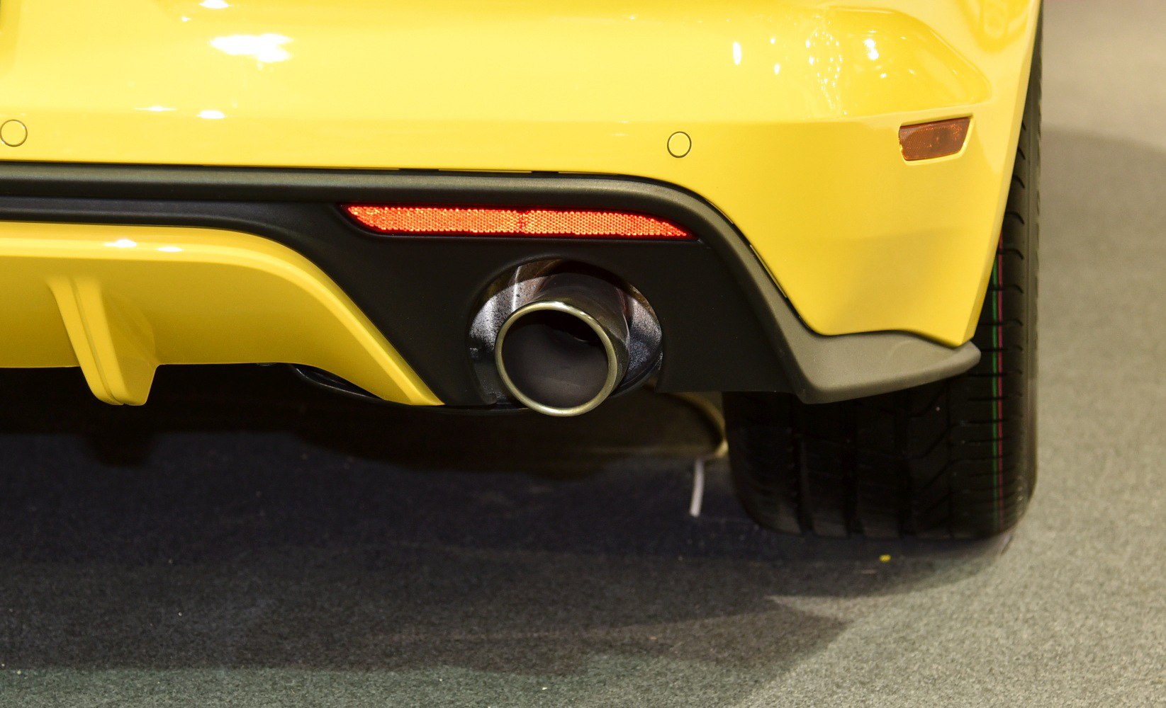 Close-up of rear exhaust pipe and bumper diffuser with reflector and tire