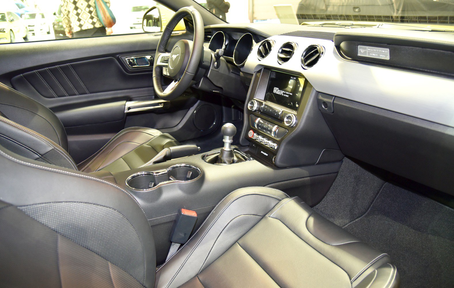 Manual gear shifter, round air vents, leather seats in a car interior