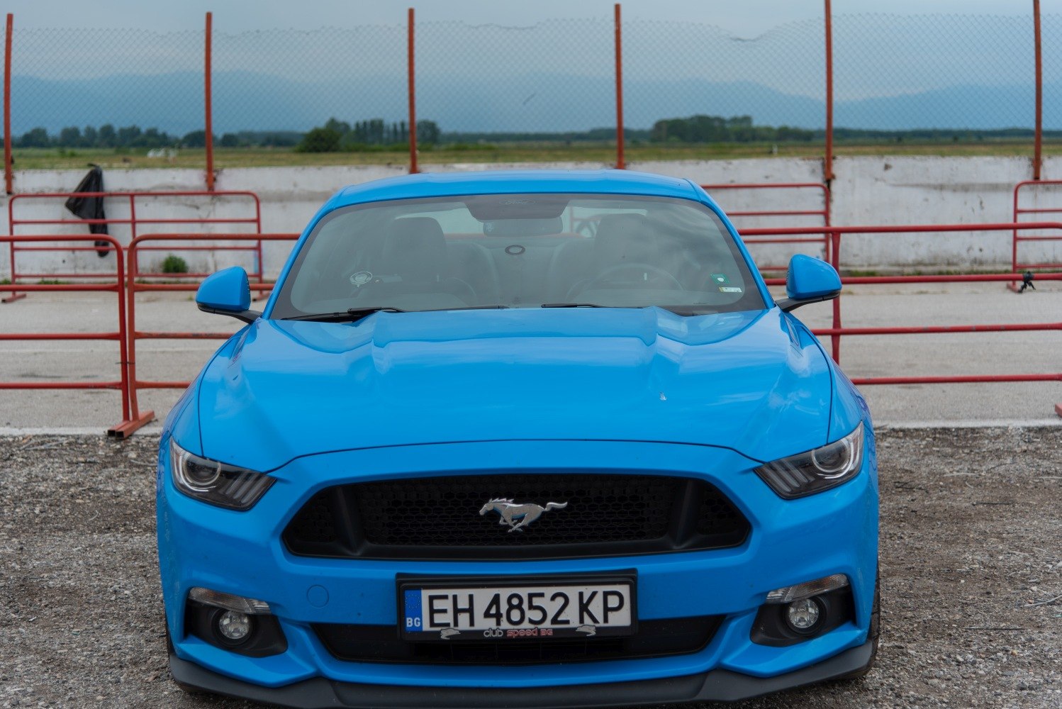 Front view of a blue muscle car with iconic grille and sharp headlights