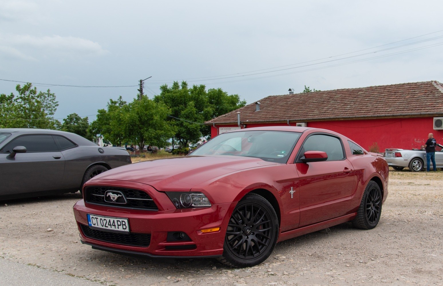 Red coupe with black wheels and Mustang emblem front view