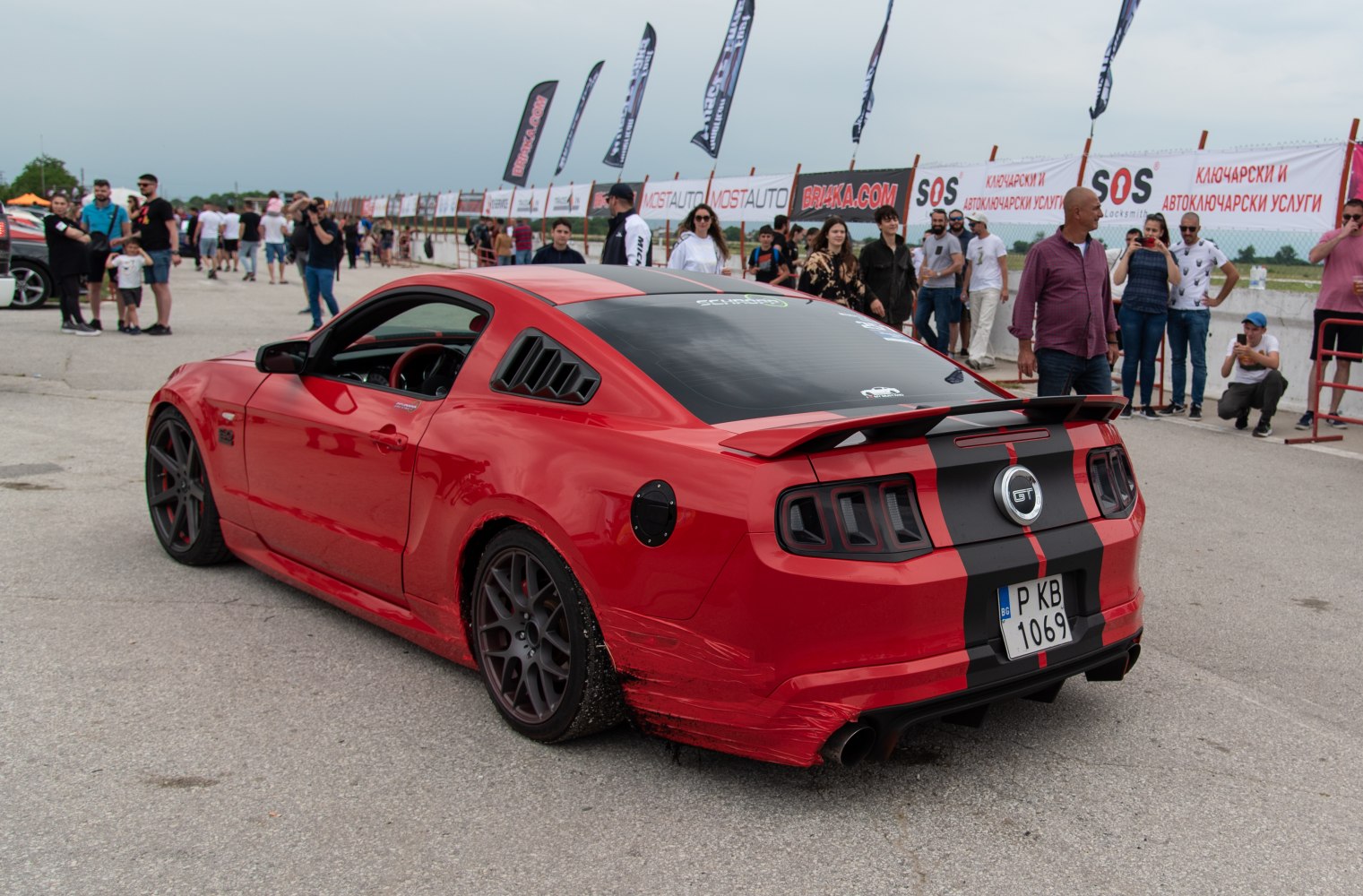 Red muscle car rear with racing stripes, spoiler, rear window vent
