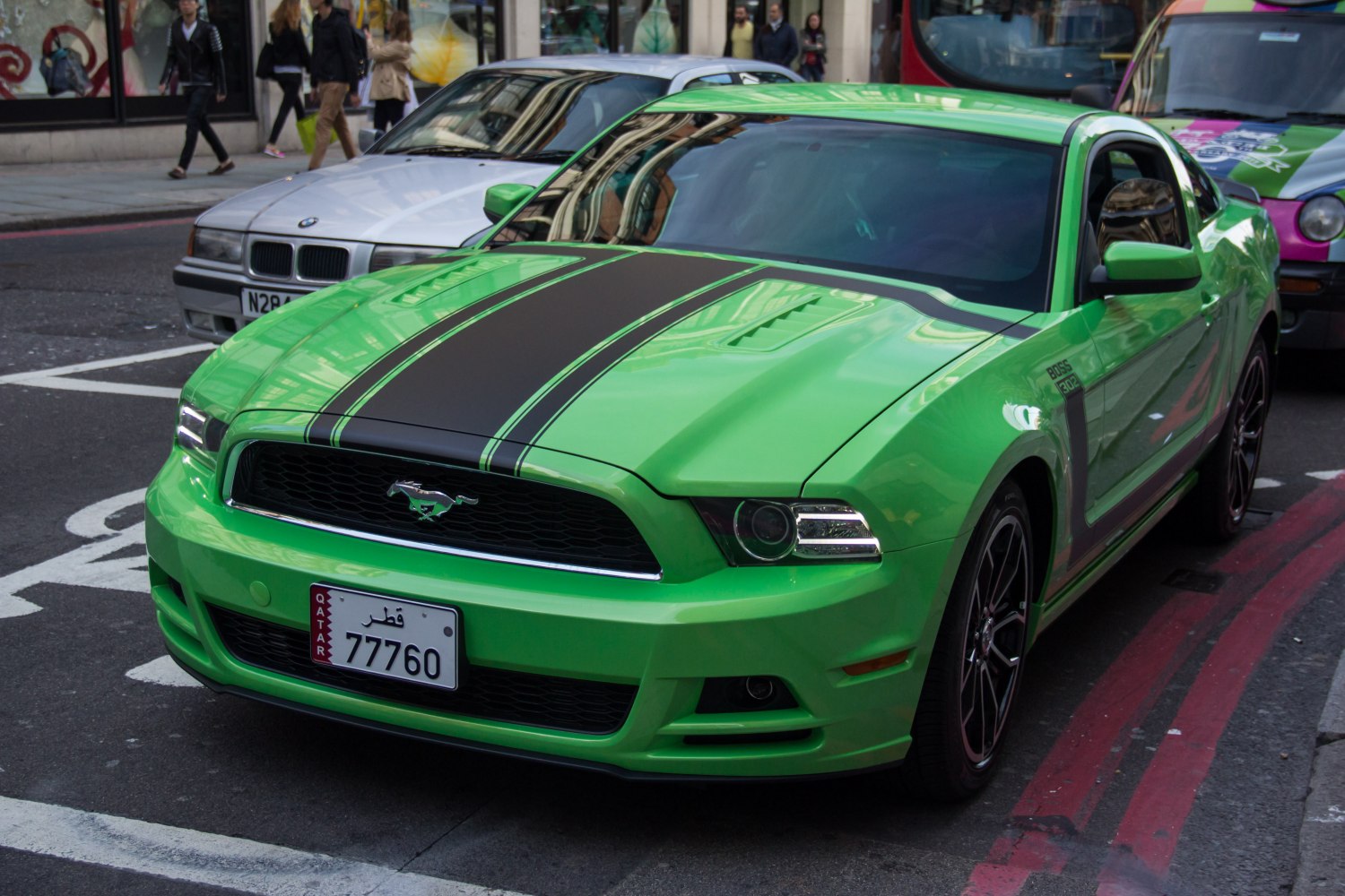 Bright green muscle car with black dual hood stripes on street