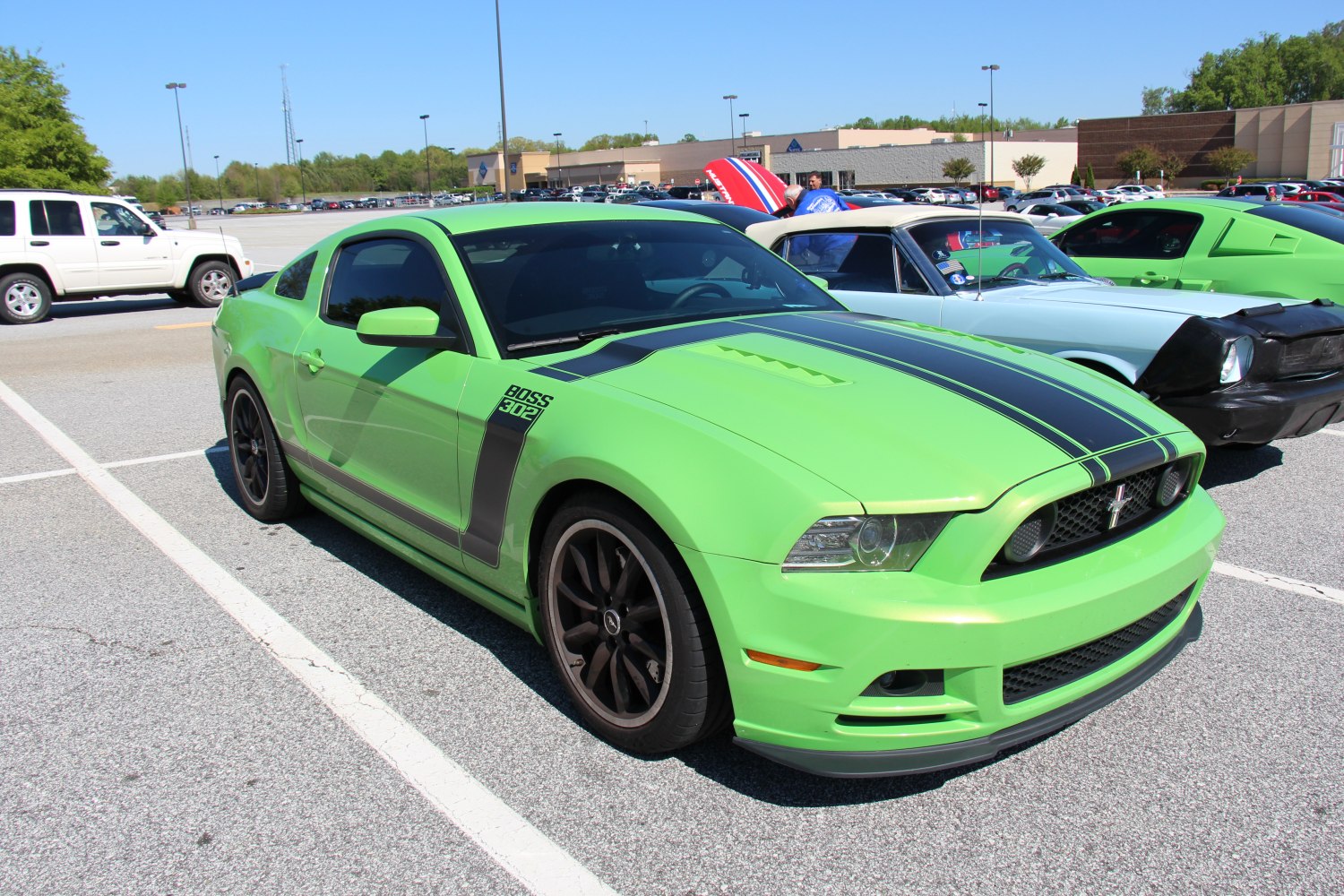 Green coupe with black racing stripes and sporty black wheels