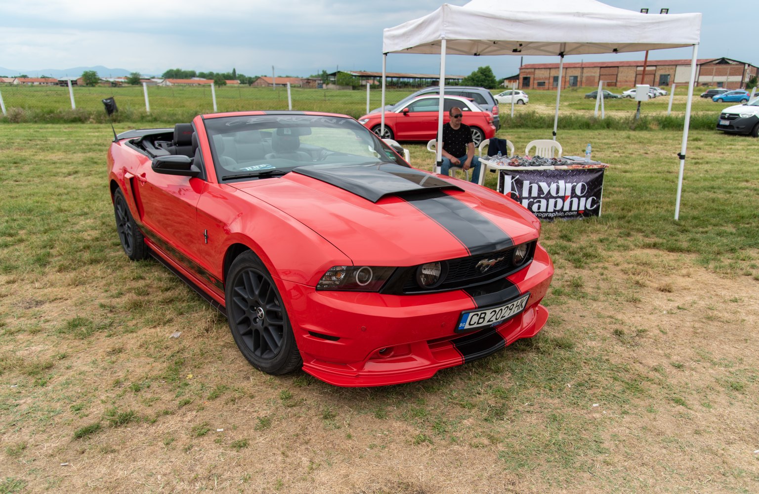 Red convertible with black racing stripes and hood scoop