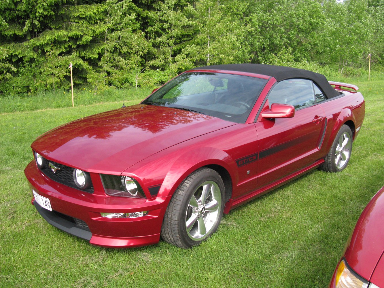 Red convertible with black soft top and sporty front grille